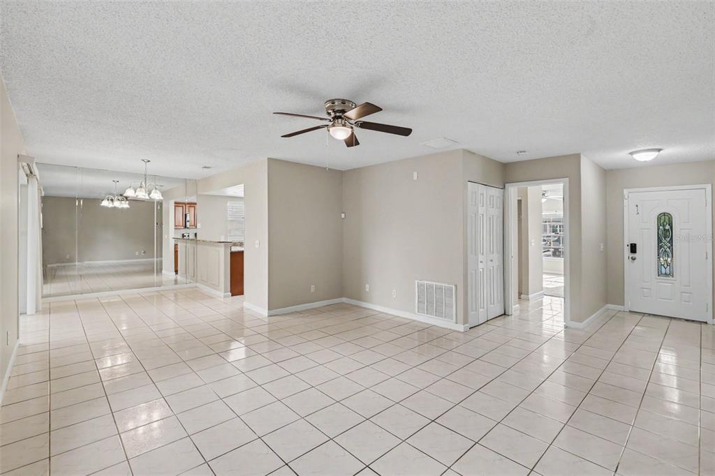 A tiled living area features a ceiling fan, a mirrored wall, and an entryway door — 301 REGAL PARK DRIVE, VALRICO, FL