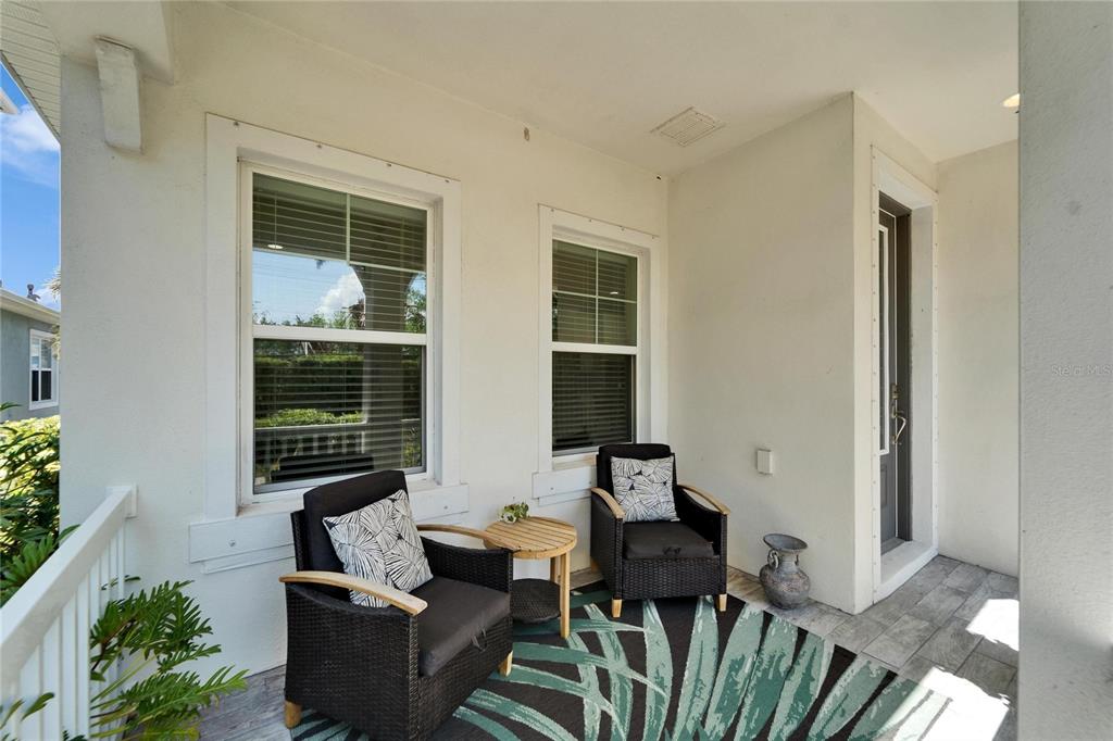 A covered front porch features two wicker chairs, a small table, and a patterned rug — 606 WINTERSIDE DRIVE, APOLLO BEACH, FL