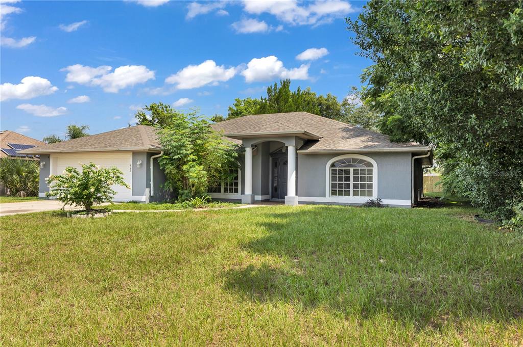 A single-story gray house with a two-car garage, white columns, and a large front lawn — 2752 N JULIET DRIVE, DELTONA, FL