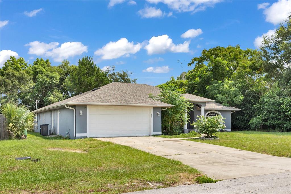 A single-story house with a two-car garage, gray stucco siding, and a concrete driveway — 2752 N JULIET DRIVE, DELTONA, FL