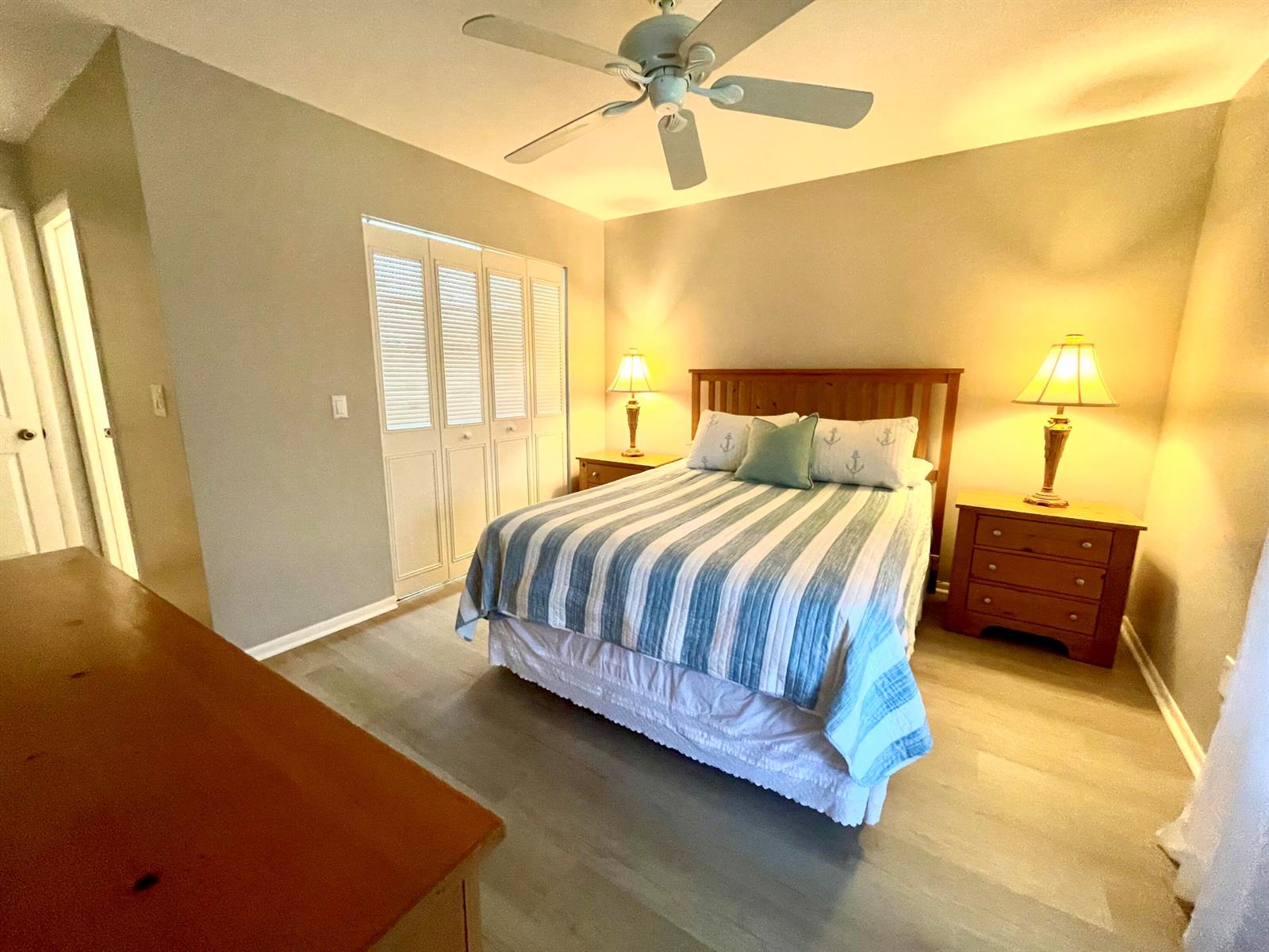 A bedroom features a bed with a striped quilt, two nightstands with lamps, and a ceiling fan — 2929 SE Ocean Boulevard # 117, Stuart FL 34996, STUART, FL