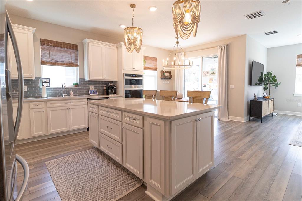 A kitchen with white cabinets, a large central island, and wood-look flooring — 12951 BROOKSIDE MOSS DRIVE, RIVERVIEW, FL