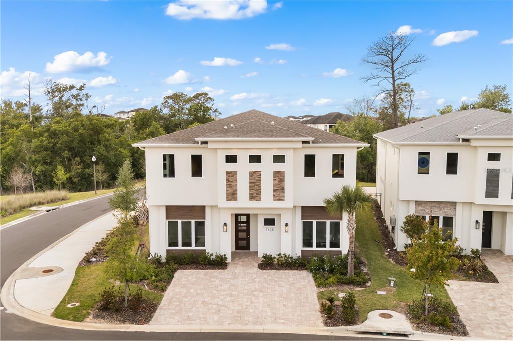 A two-story house with a white stucco exterior, stone accents, and a paved driveway — 7638 WHITEMARSH WAY, KISSIMMEE, FL