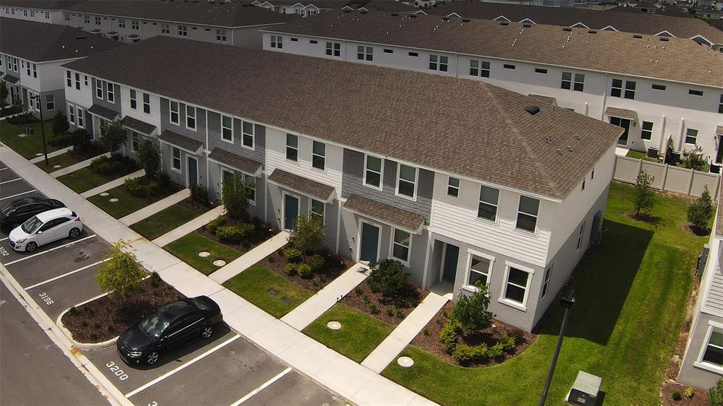 An aerial view shows a row of multi-story townhouses with gray siding and parking spaces — 3208 SKYLINE LOOP, POINCIANA, FL
