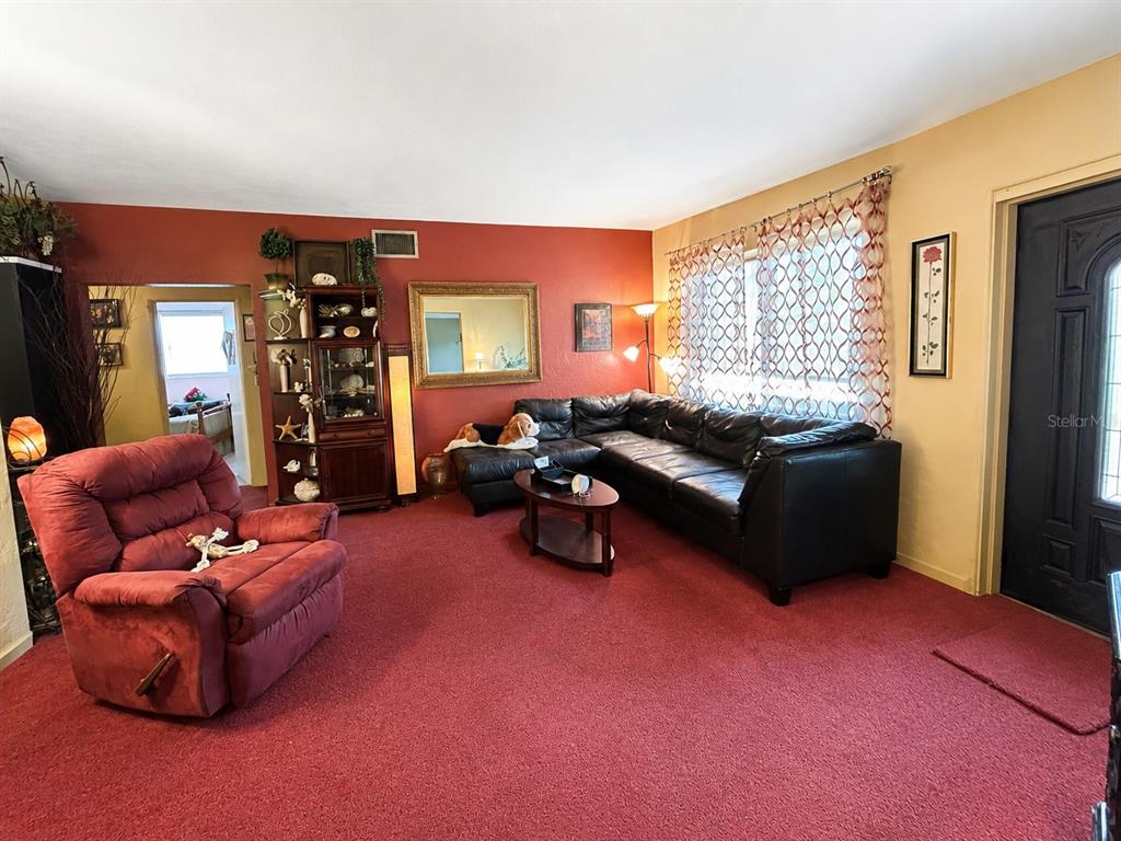 A living room features red carpeting, a black sectional sofa, and a red recliner — 608 DIXIE LANE, SOUTH DAYTONA, FL