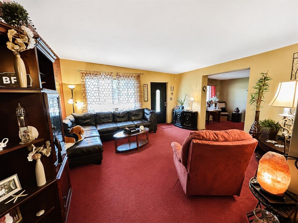 A living room features red carpeting, a black leather sectional, and a red armchair — 608 DIXIE LANE, SOUTH DAYTONA, FL