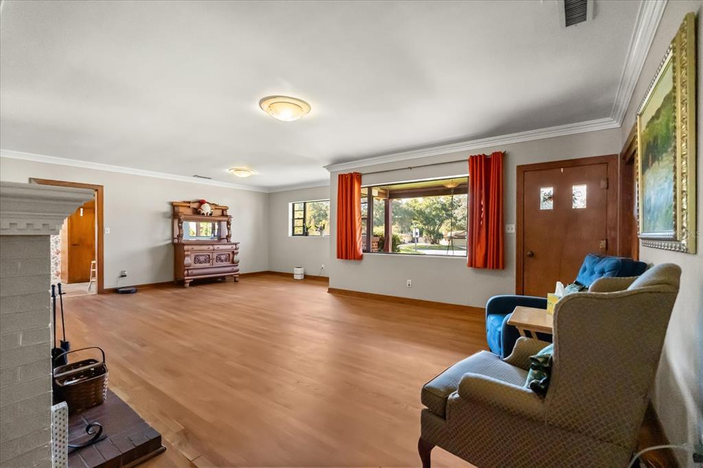 A living room features hardwood floors, a brick fireplace, orange curtains, and a wooden hutch — 205 SURPRISE DRIVE, WINTER GARDEN, FL