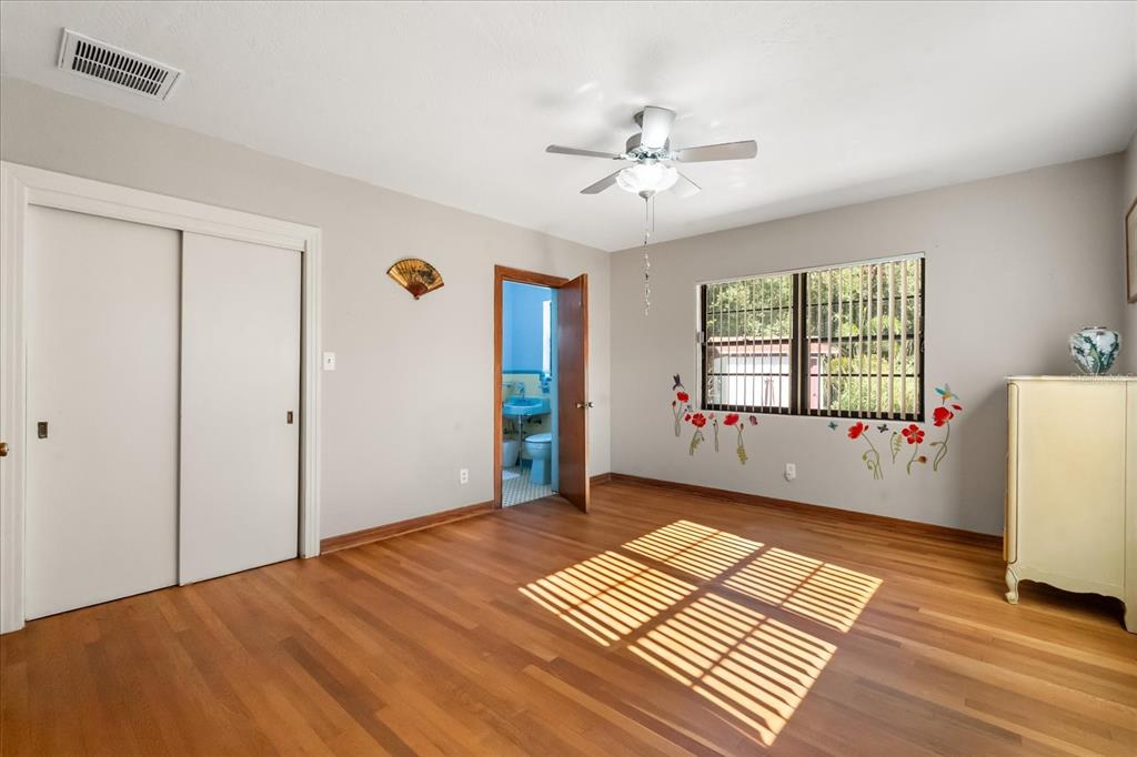 A bedroom with hardwood floors, a ceiling fan, a sliding closet, and an attached bathroom — 205 SURPRISE DRIVE, WINTER GARDEN, FL