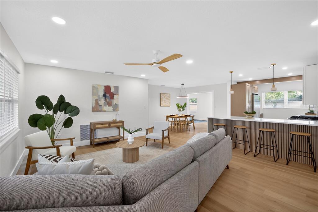 An open-concept living room and kitchen feature light wood flooring, neutral walls, and modern furniture — 2091 62ND PLACE S, ST PETERSBURG, FL