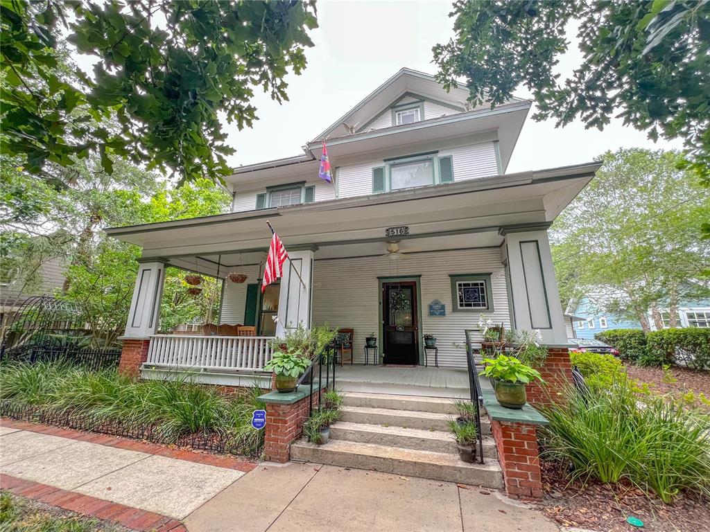 A two-story house with a large front porch, brick pillars, and white siding — 516 NE 4TH STREET, GAINESVILLE, FL