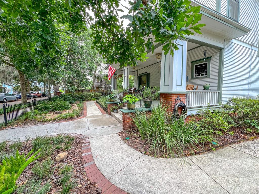 A white house with a brick-trimmed concrete walkway and a covered front porch — 516 NE 4TH STREET, GAINESVILLE, FL