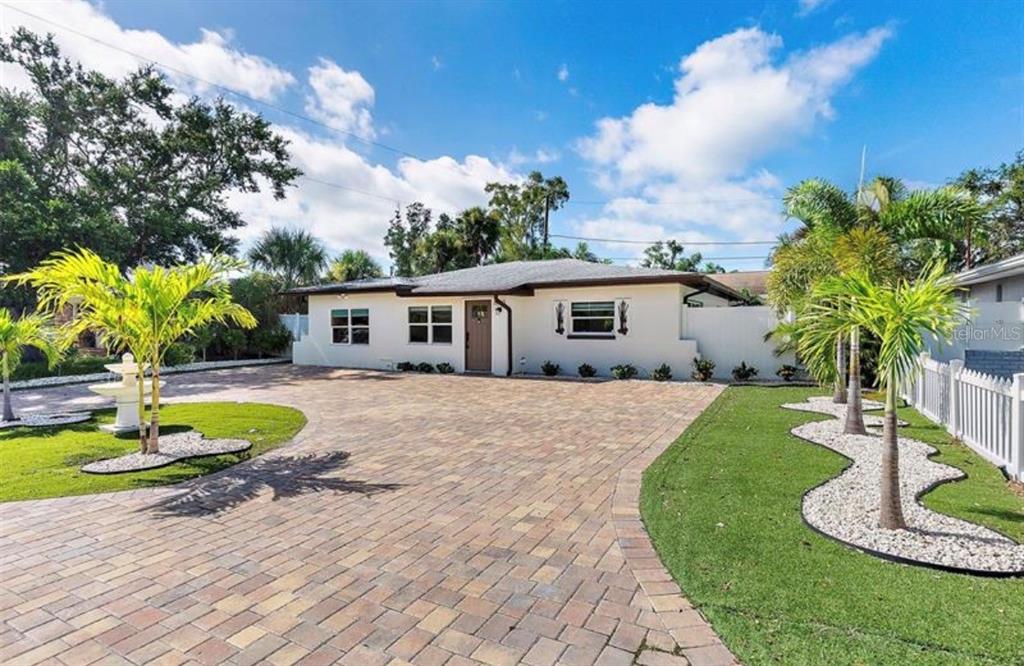A single-story house with a large paver driveway, palm trees, and a white privacy wall — 6750 W FLAMINGO WAY S, ST PETERSBURG, FL
