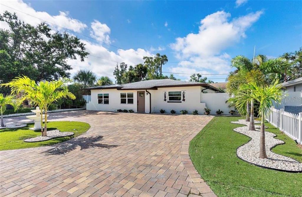 A single-story house with a paved driveway, palm trees, and a white fence — 6750 W FLAMINGO WAY S, ST PETERSBURG, FL