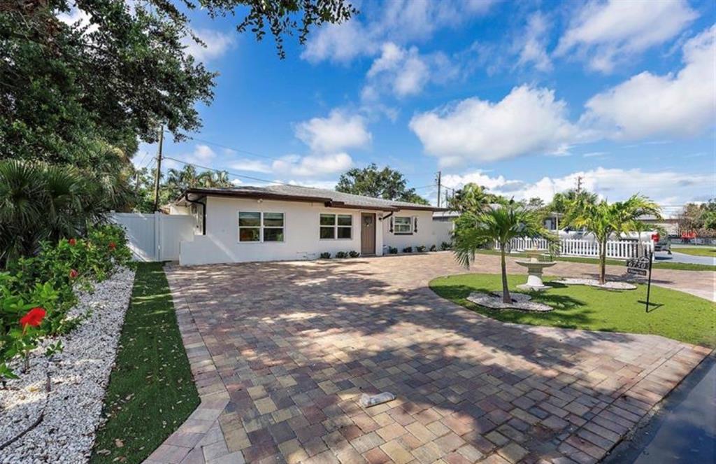 A single-story house with a large paved driveway, a small lawn, and palm trees — 6750 W FLAMINGO WAY S, ST PETERSBURG, FL
