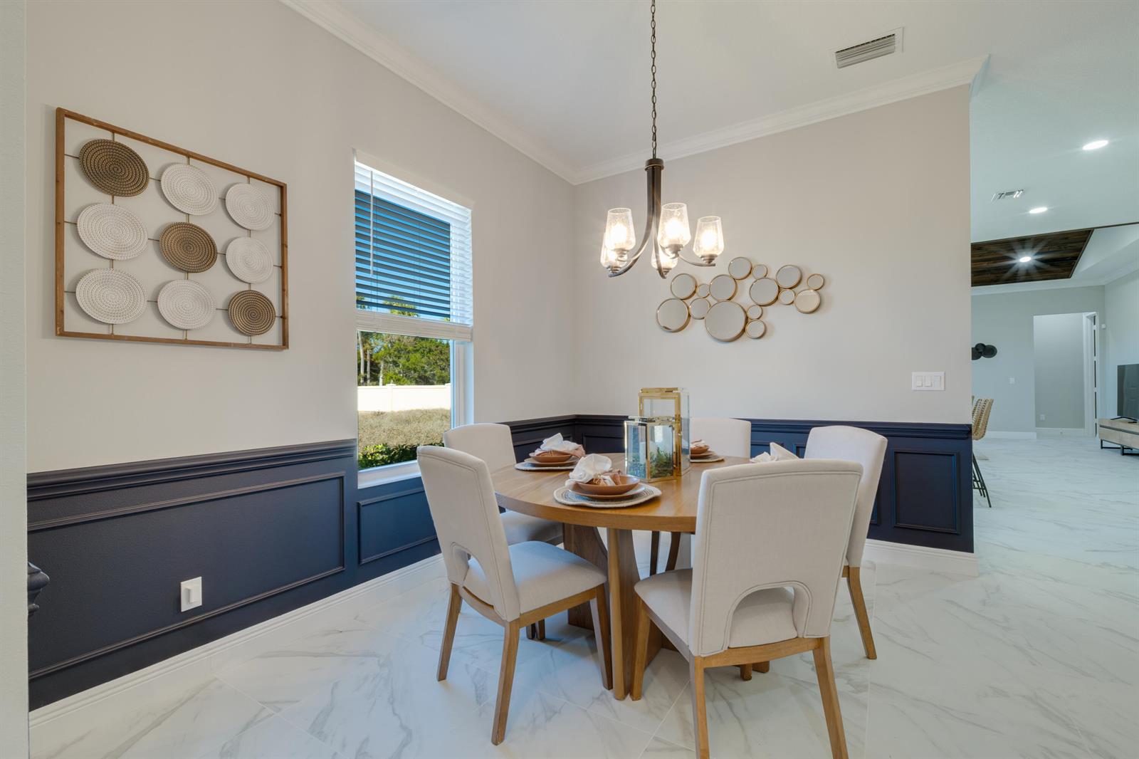 A dining room features a round wooden table, upholstered chairs, and blue wainscoting — 2005 Bridgepointe Circle # 97, Vero Beach FL 32967, VERO BEACH, FL