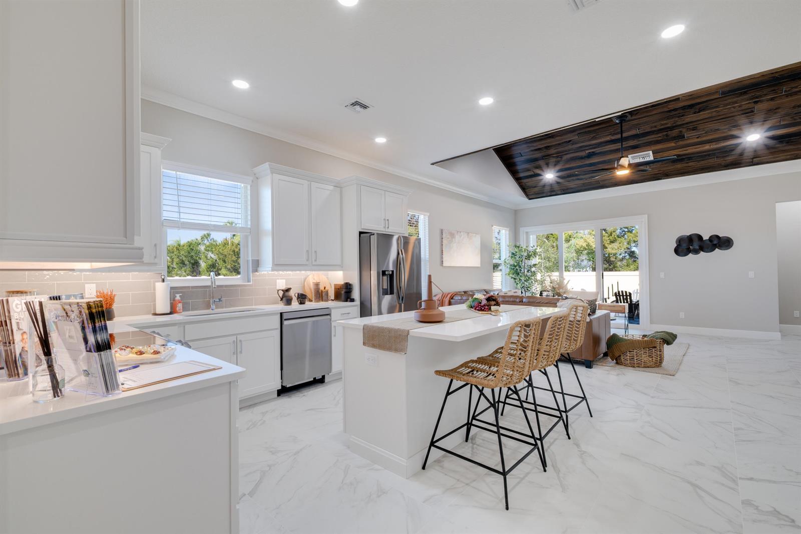 A modern kitchen with white cabinets, a central island, and a dark wood-paneled tray ceiling — 2005 Bridgepointe Circle # 97, Vero Beach FL 32967, VERO BEACH, FL