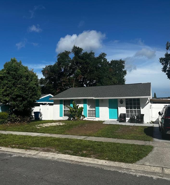 A single-story white brick house features a teal front door and matching window shutters — 16004 SADDLE CREEK DRIVE, TAMPA, FL