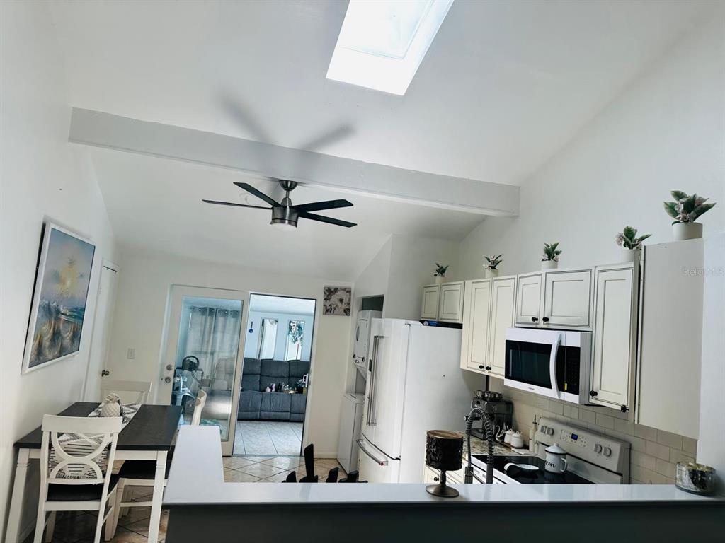 A kitchen with white cabinets and a dining area under a vaulted ceiling with skylight — 16004 SADDLE CREEK DRIVE, TAMPA, FL