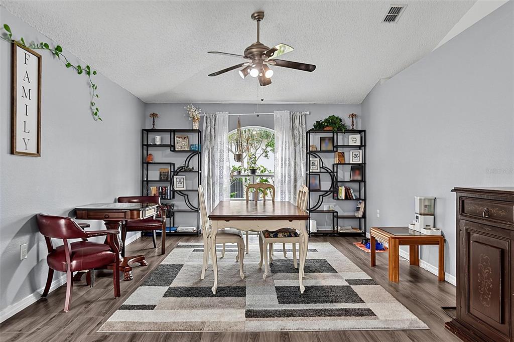 A dining room features a wooden table, chairs, metal shelving units, and a patterned area rug — 30 RYDER DRIVE, PALM COAST, FL
