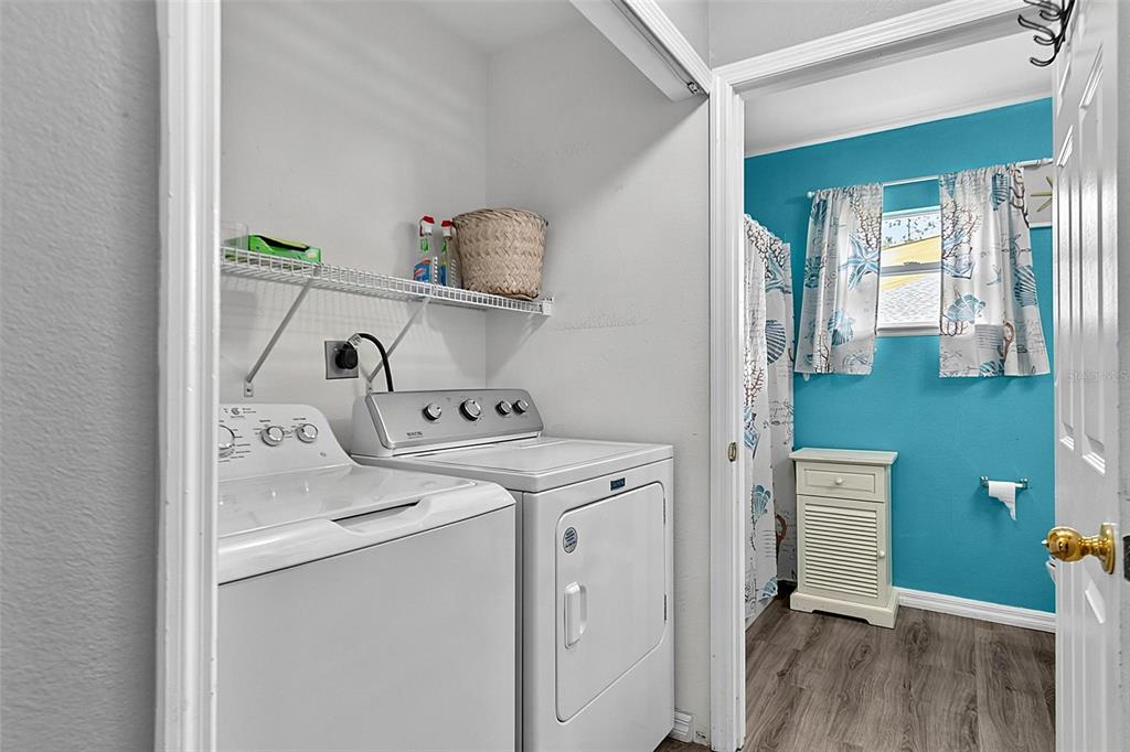 A laundry closet with a washer and dryer sits beside a bathroom with blue walls — 30 RYDER DRIVE, PALM COAST, FL
