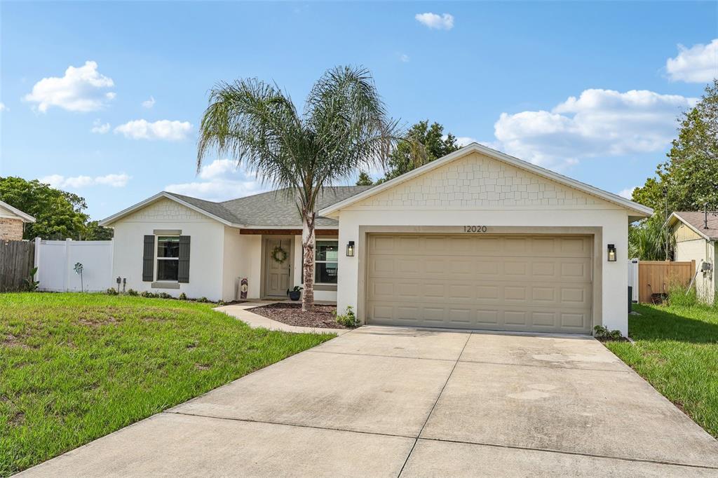 A single-story house with a beige garage, a palm tree, and a concrete driveway — 12020 VIRGINIA DRIVE, LEESBURG, FL
