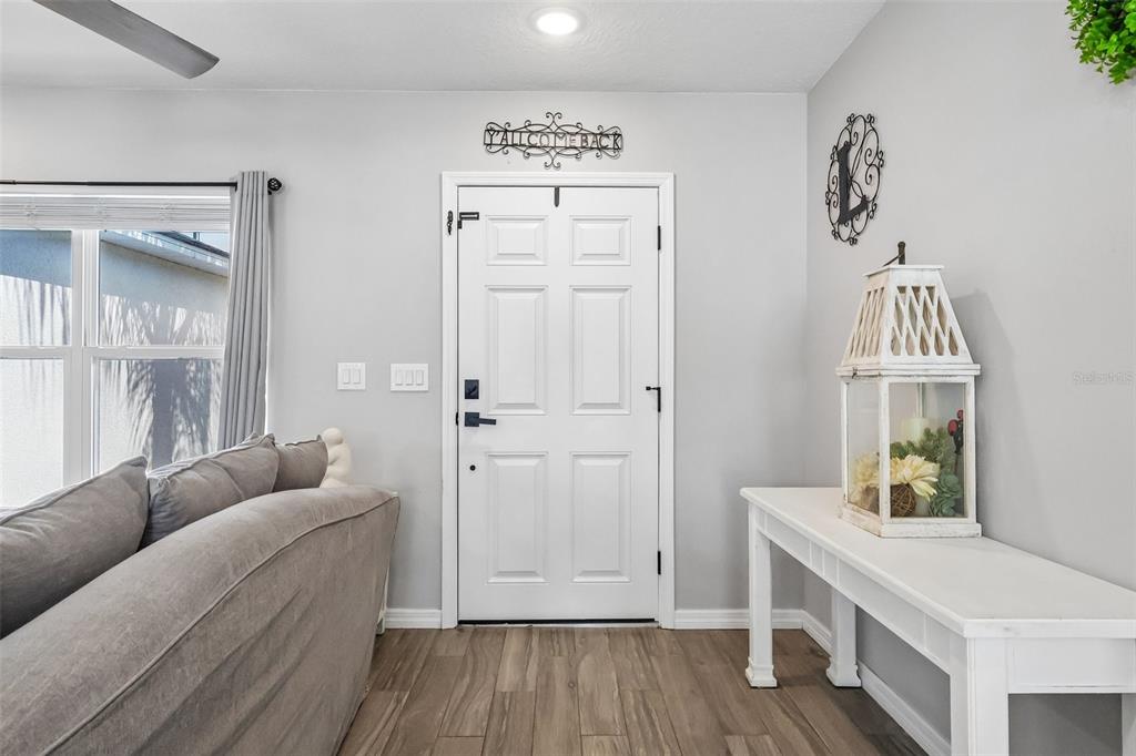 A living room entryway features a white door, light wood flooring, and a console table — 12020 VIRGINIA DRIVE, LEESBURG, FL