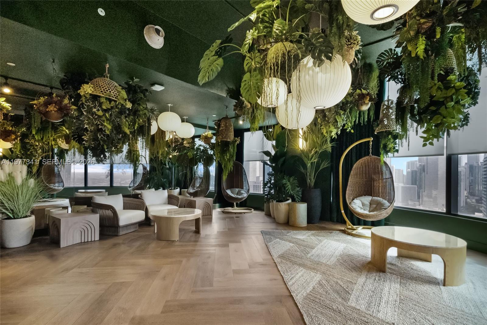 A lounge area features hanging rattan chairs, abundant indoor greenery, and a dark green ceiling — 121 NE 5 ST # 1500, Miami FL 33132, MIAMI, FL