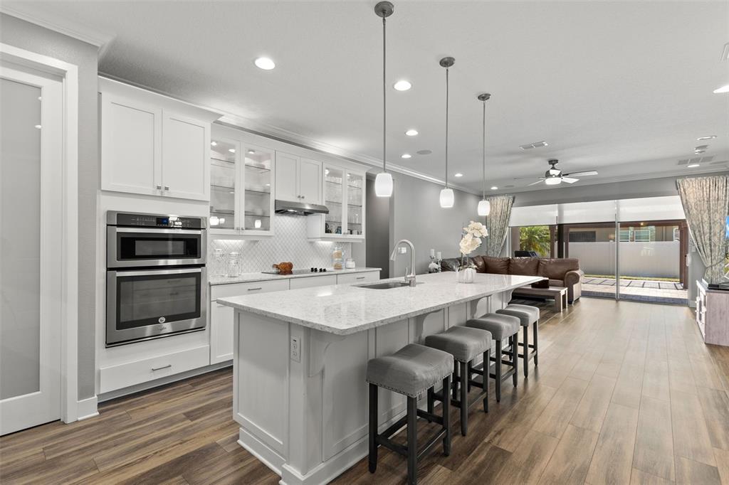 A modern kitchen features white cabinetry, a large granite island with bar seating, and stainless appliances — 12109 NIGHT JASMINE COVE, RIVERVIEW, FL