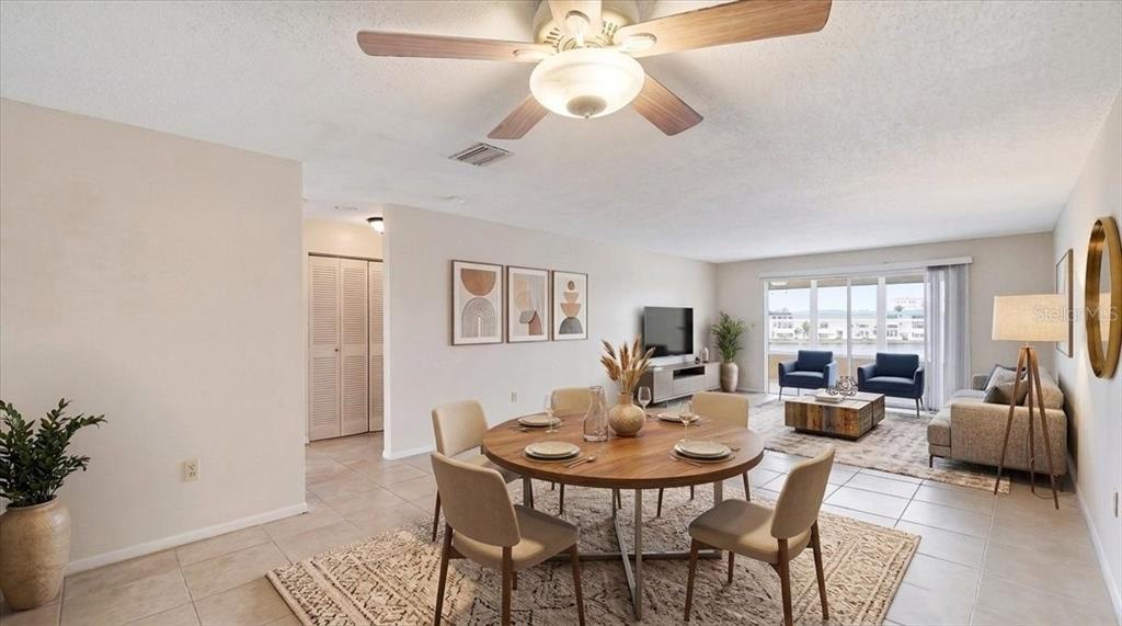 A dining area with a round wooden table sits adjacent to a living room — 5925 SHORE BOULEVARD S UNIT 302, GULFPORT, FL