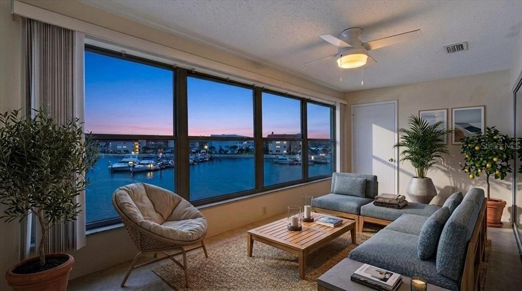 A sunroom with a sectional sofa, coffee table, and large windows overlooking a marina — 5925 SHORE BOULEVARD S UNIT 302, GULFPORT, FL