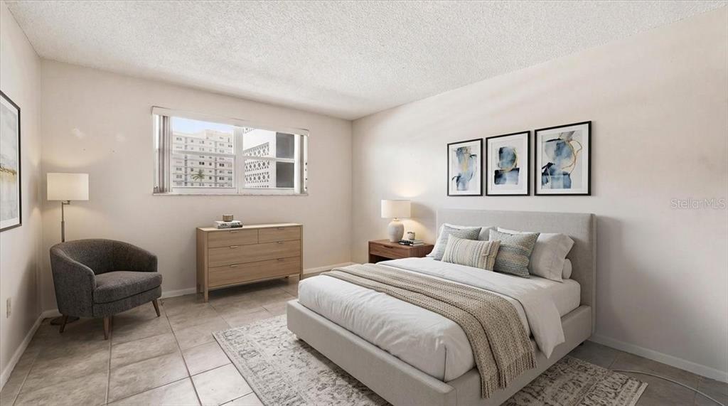 A bedroom features a bed, a dresser, an armchair, and a window with city views — 5925 SHORE BOULEVARD S UNIT 302, GULFPORT, FL