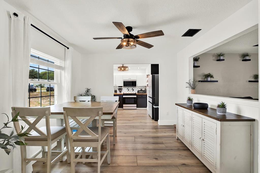 A dining room with a wooden table, white chairs, and a view into the kitchen — 4118 RAMONA DRIVE, SPRING HILL, FL