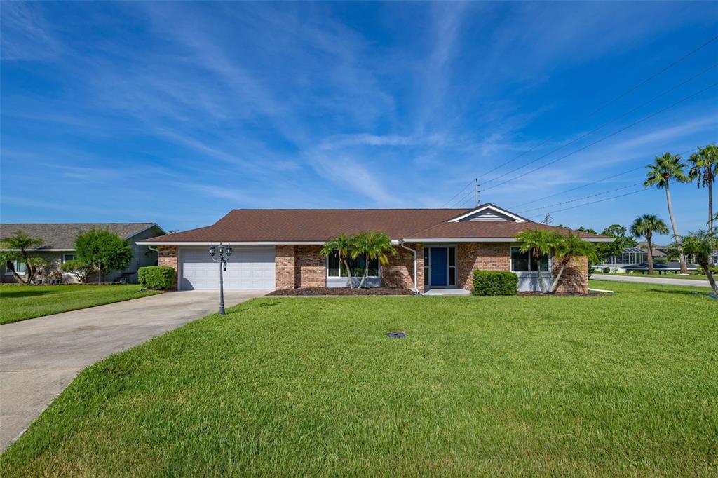 A single-story brick house with a brown roof, a two-car garage, and a front lawn — 2 CLAYMONT COURT S, PALM COAST, FL