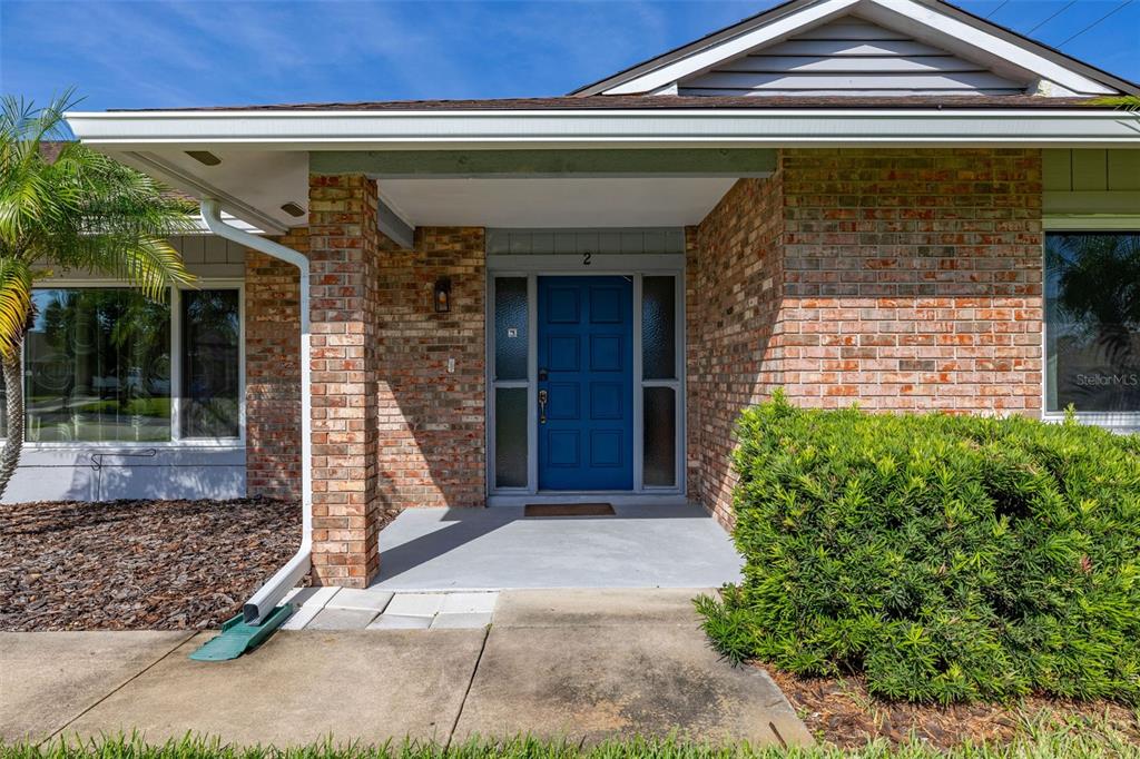 The exterior of a brick house features a blue front door and a covered porch — 2 CLAYMONT COURT S, PALM COAST, FL