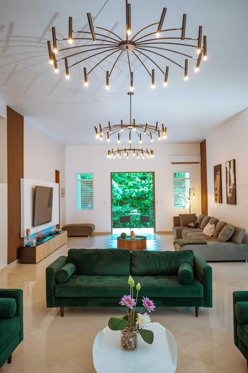 A living room features two modern sputnik chandeliers, a green velvet sofa, and a television — CARR 799 KM 29.5 BO RIO CANAS SECT LA PONDEROSA UNIT 4, CAGUAS, PR