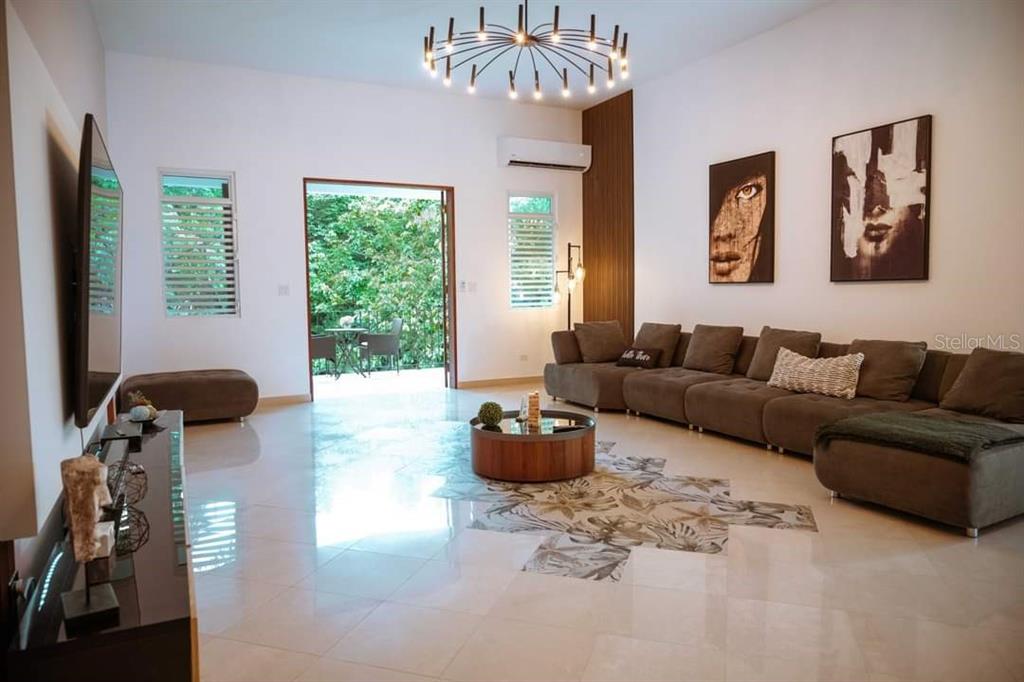 A modern living room features a large brown sectional sofa, tile floors, and a chandelier — CARR 799 KM 29.5 BO RIO CANAS SECT LA PONDEROSA UNIT 4, CAGUAS, PR