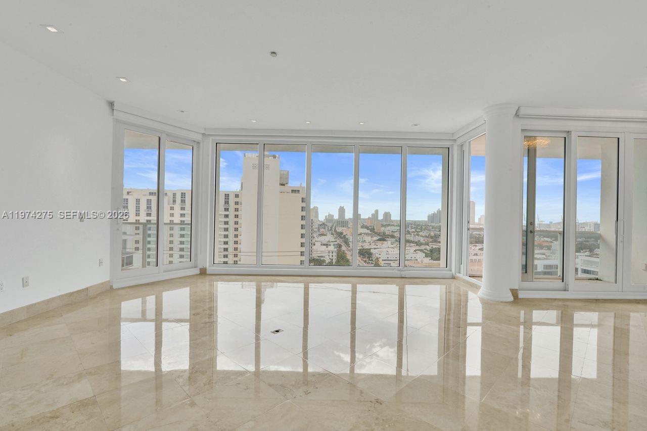 A bright, empty room features polished marble floors, floor-to-ceiling windows, and a city view — 100 Lincoln Rd, Miami Beach FL 33139, MIAMI BEACH, FL