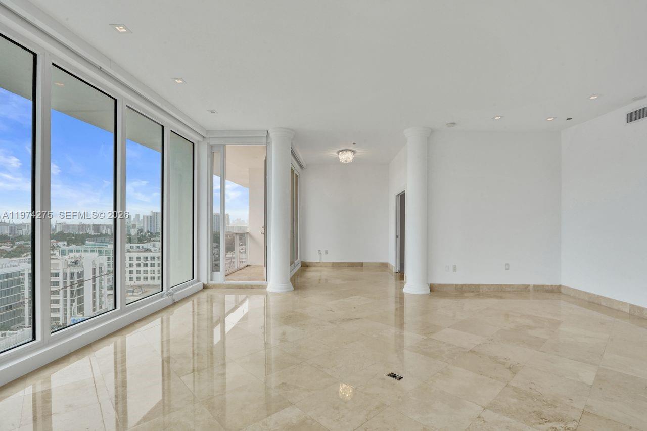 An empty room features marble flooring, two white columns, and floor-to-ceiling windows overlooking a city — 100 Lincoln Rd, Miami Beach FL 33139, MIAMI BEACH, FL