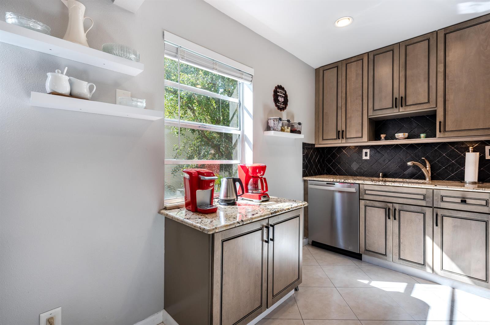 A kitchen features wood cabinets, granite countertops, stainless steel appliances, and a window — 184 Piedmont D # D, Delray Beach FL 33484, DELRAY BEACH, FL