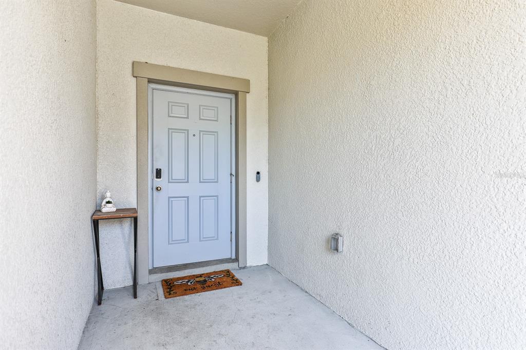 A light blue front door with a small side table and welcome mat on a porch — 14323 EASY GOER STREET, RUSKIN, FL