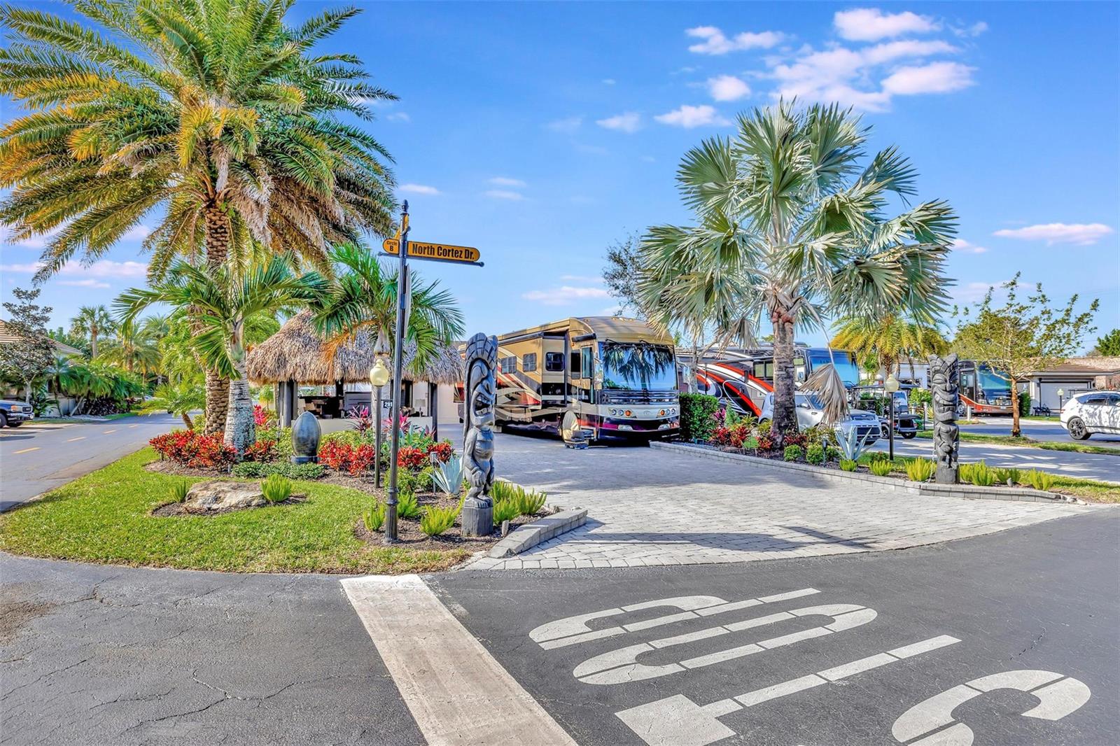 A paved driveway features a large motorhome parked next to tiki statues and palm trees — 291 N Cortez Drive # 291, Margate FL 33068, MARGATE, FL