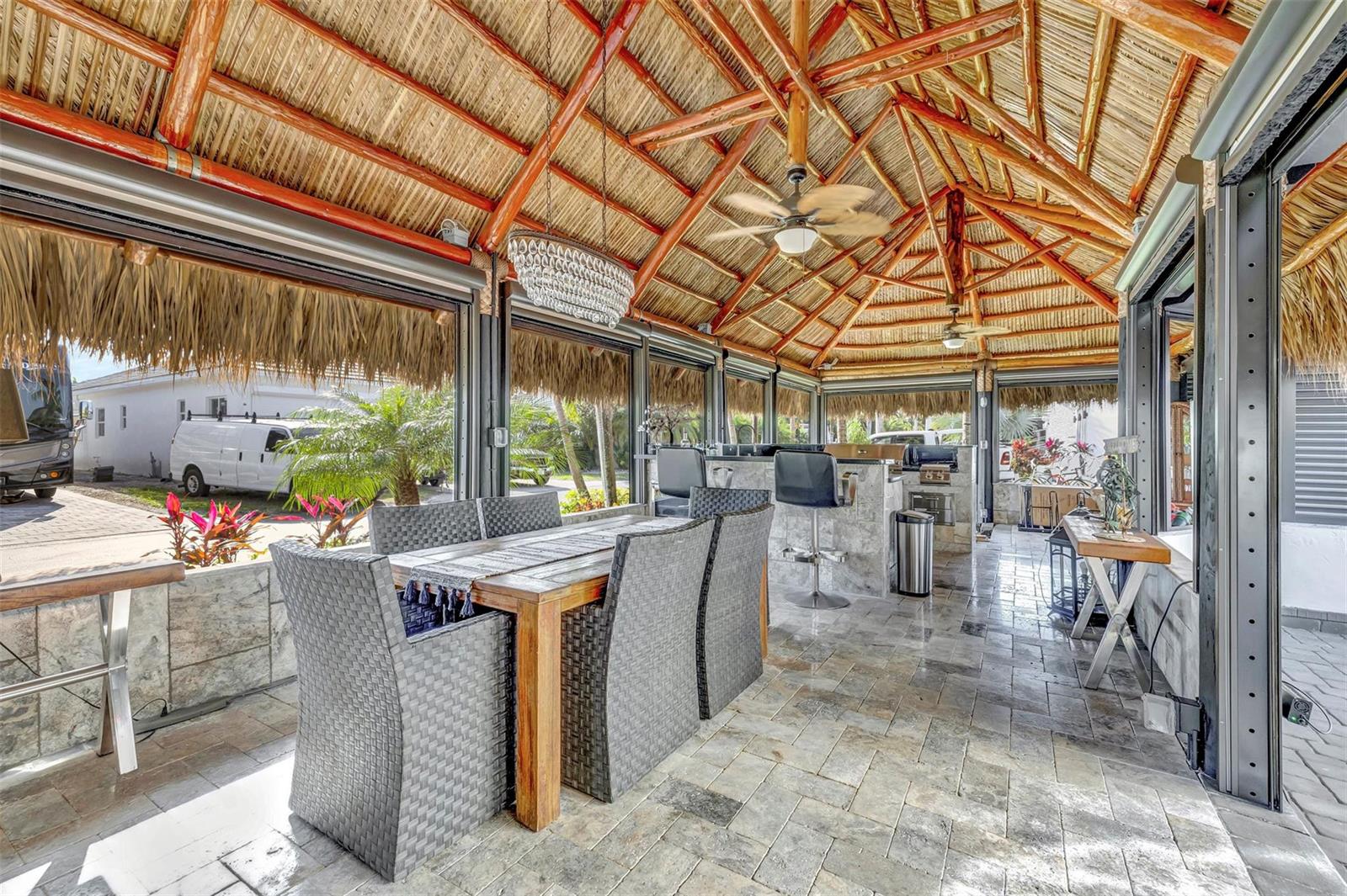 An open-air patio features a thatched roof, stone flooring, a dining set, and outdoor kitchen — 291 N Cortez Drive # 291, Margate FL 33068, MARGATE, FL