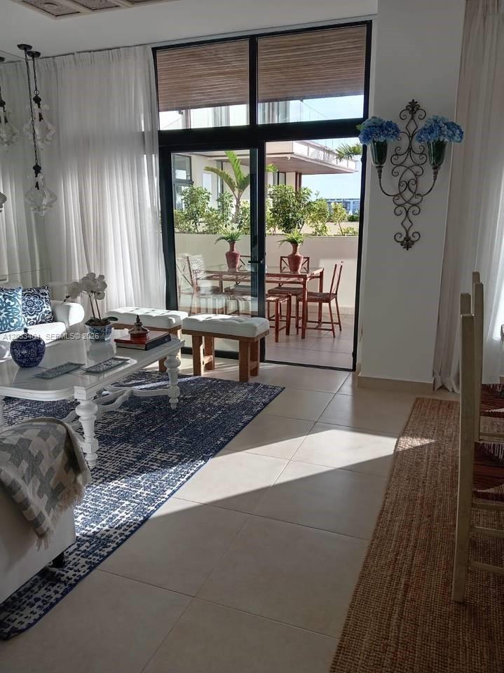 A living room with a blue patterned rug opens onto a balcony with dining furniture — 1 1 # 205, FL, FL