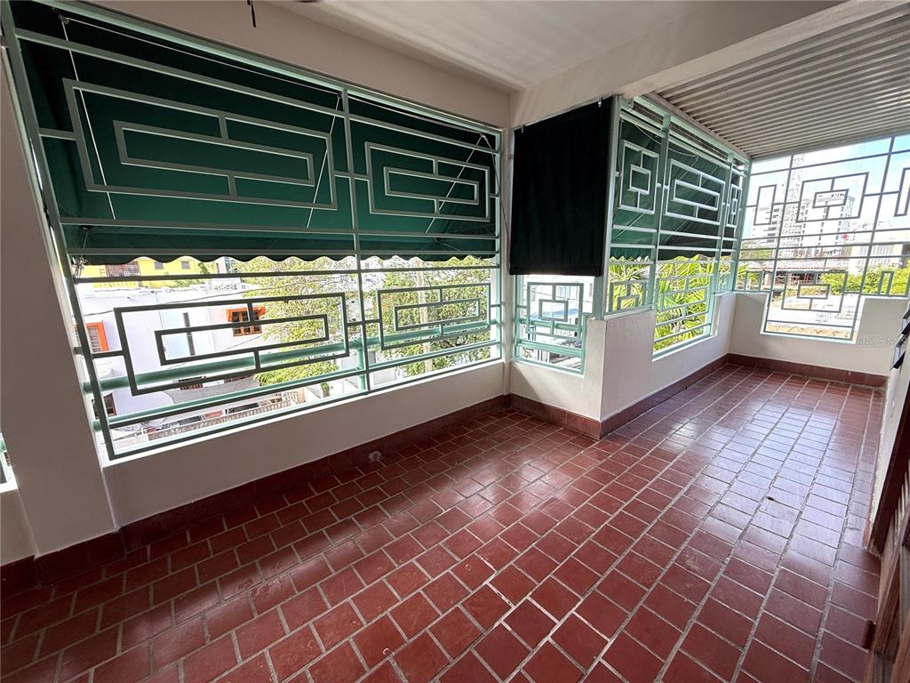 A covered balcony features red tile flooring and decorative green metal security grilles — 1507 LAS MARÍAS, SAN JUAN, PR