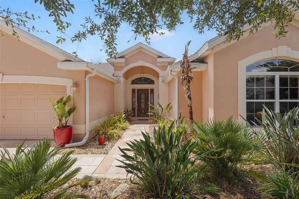 The exterior of a peach-colored house features a paved walkway leading to the front entrance — 2252 CENTRAL STREET, THE VILLAGES, FL