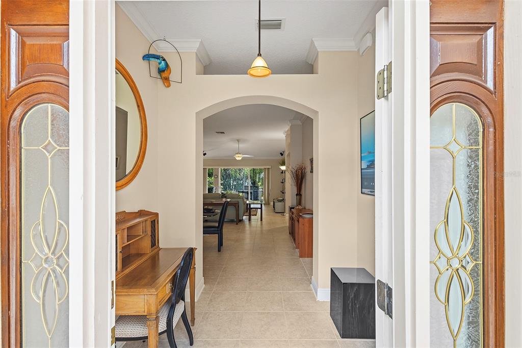 A view through an open front door into a tiled foyer with an arched entryway — 2252 CENTRAL STREET, THE VILLAGES, FL