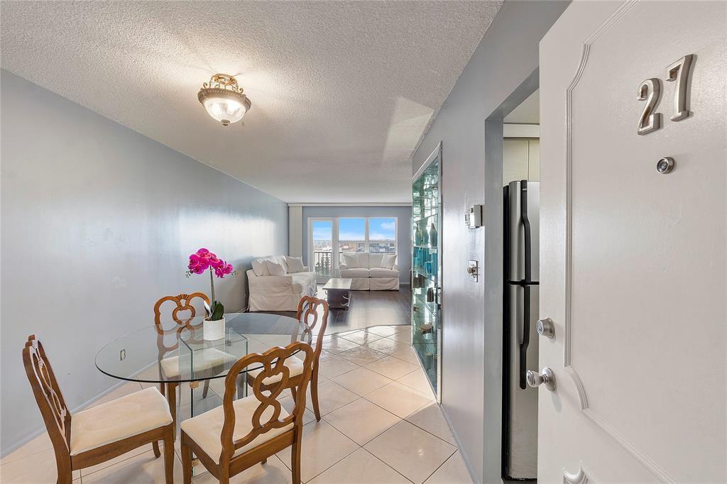 A dining area with a glass table leads into a living room with balcony access — 405 N Ocean Boulevard, Pompano Beach FL 33062, POMPANO BEACH, FL