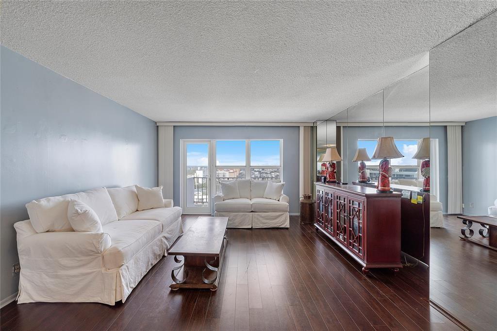 A living room with white sofas, a wooden coffee table, dark floors, and mirrored walls — 405 N Ocean Boulevard, Pompano Beach FL 33062, POMPANO BEACH, FL