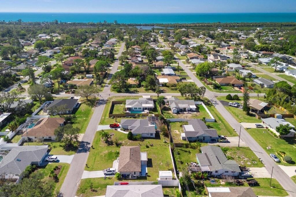 An aerial view of a coastal neighborhood featuring single-family homes, paved streets, and green lawns — 4731 EGRET ROAD, VENICE, FL