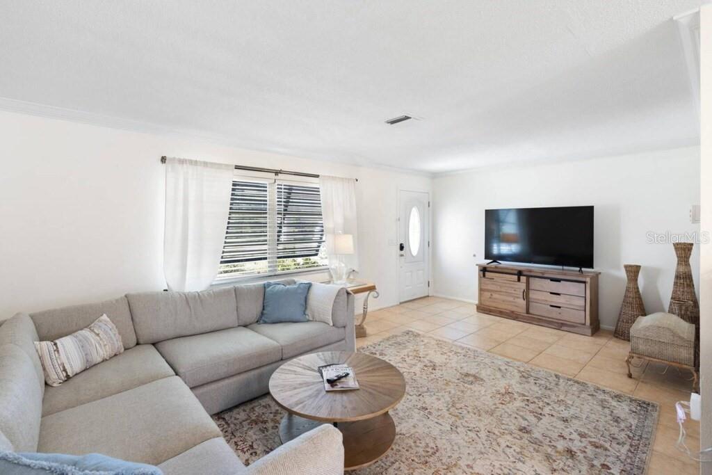 A living room features a sectional sofa, a round coffee table, and a television console — 4731 EGRET ROAD, VENICE, FL